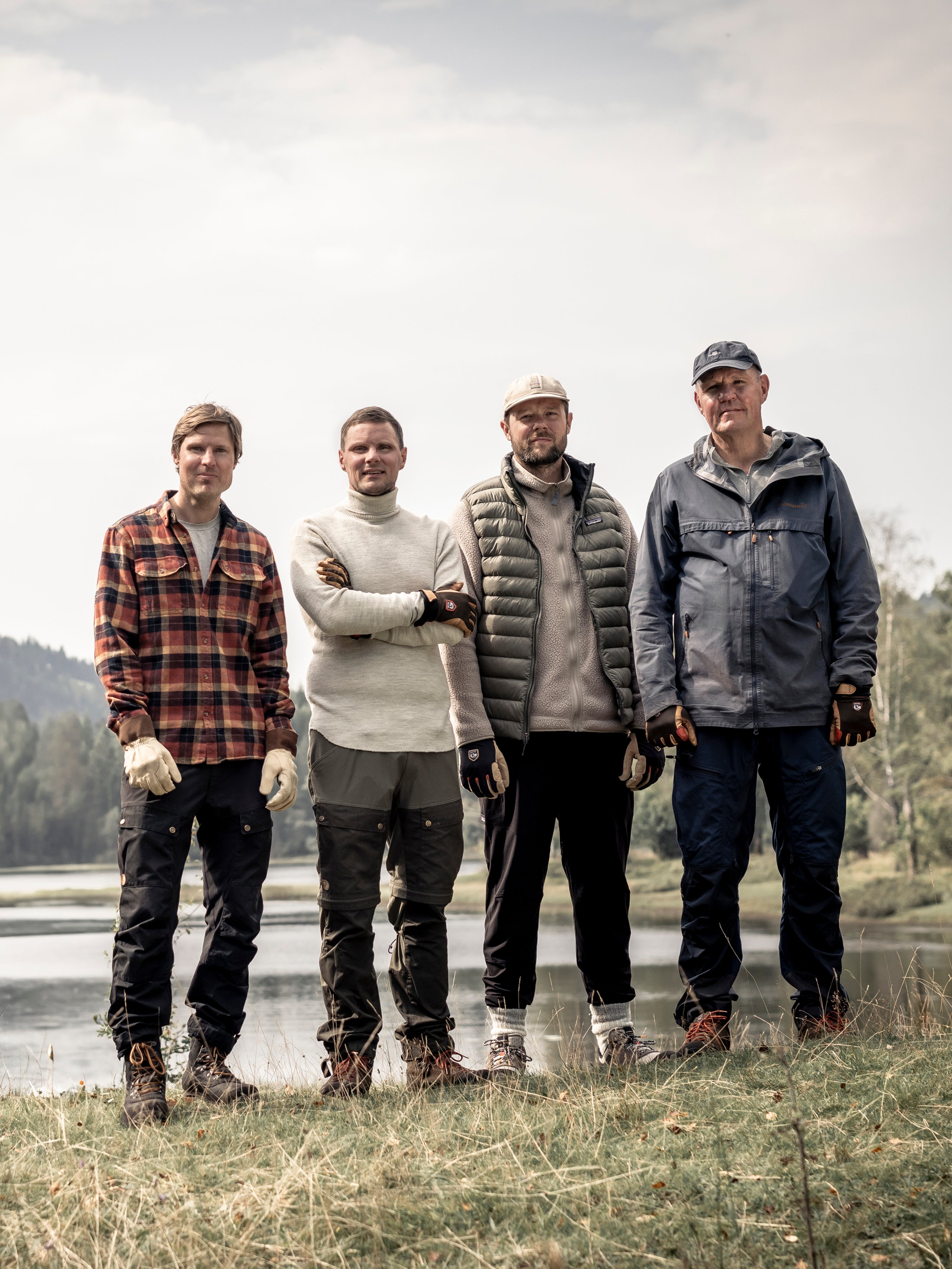 Four men standing by a lake in the Swedish countryside wearing Hestra work gloves
