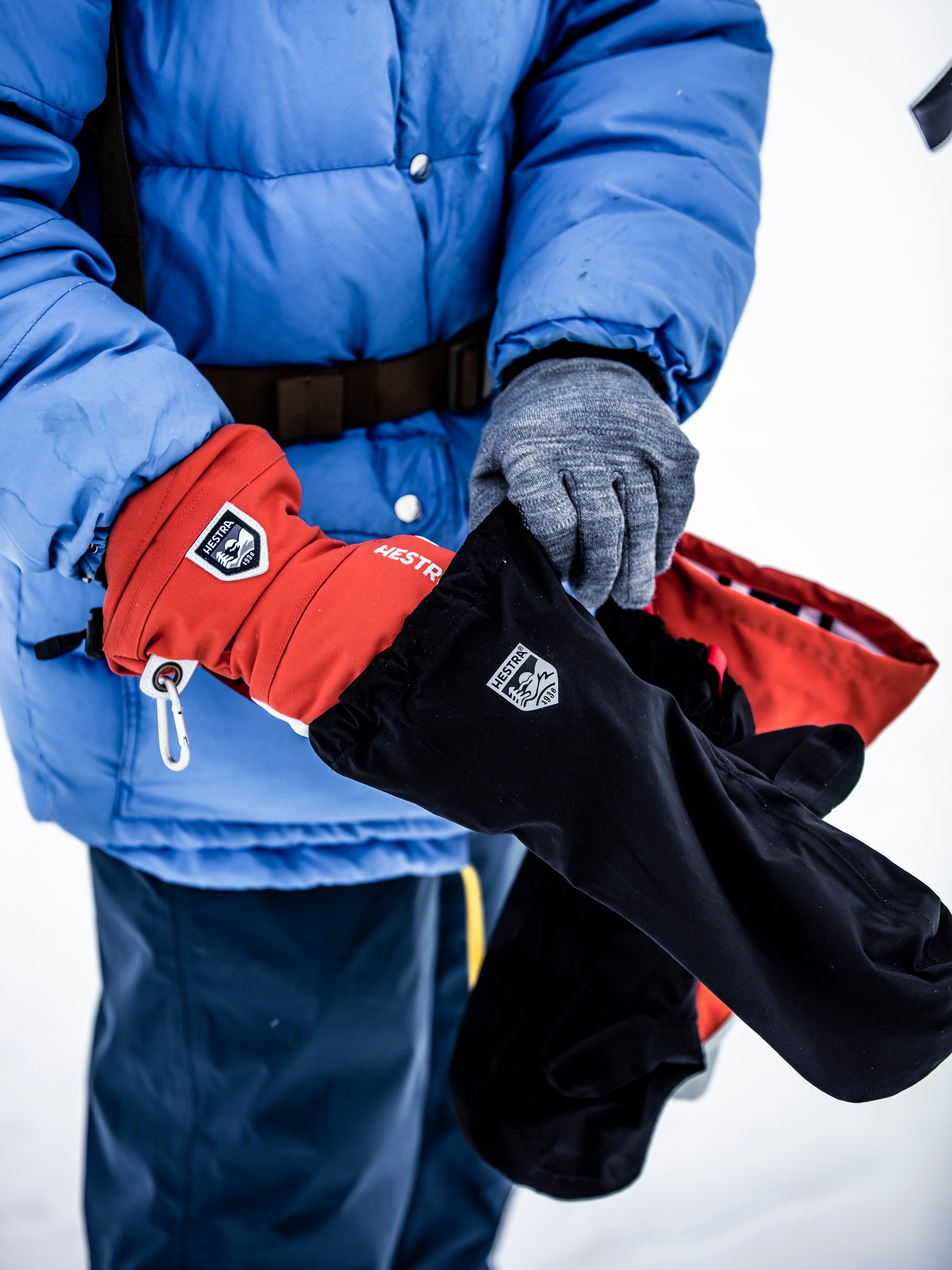 Person in a blue winter jacket showing our layering system, with liner and outer glove